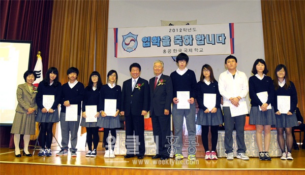 ▲ 오희석 교장(왼쪽)이 이내건·박희봉(중간) 회장이 기탁한 장학금을 한국어과정 성적우수자에게 전달한 후 기념촬영을 하고 있다.