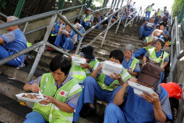 ▲ 청소노동자들이 작업환경개선을 위하여 파업중에 계단에서 점심을 먹고 있다. (사진=scmp))